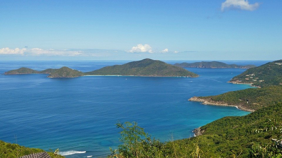 Scenic View Of Cruz Bay With Clear Blue Waters And Lush Green Islands Under A Bright Sky, Ideal For Watersports Activities.