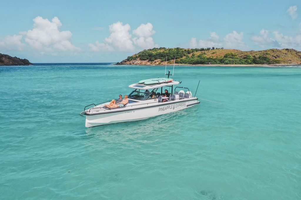 People Relaxing On A Boat Named &Quot;Pineapple Express&Quot; On Clear Turquoise Waters.