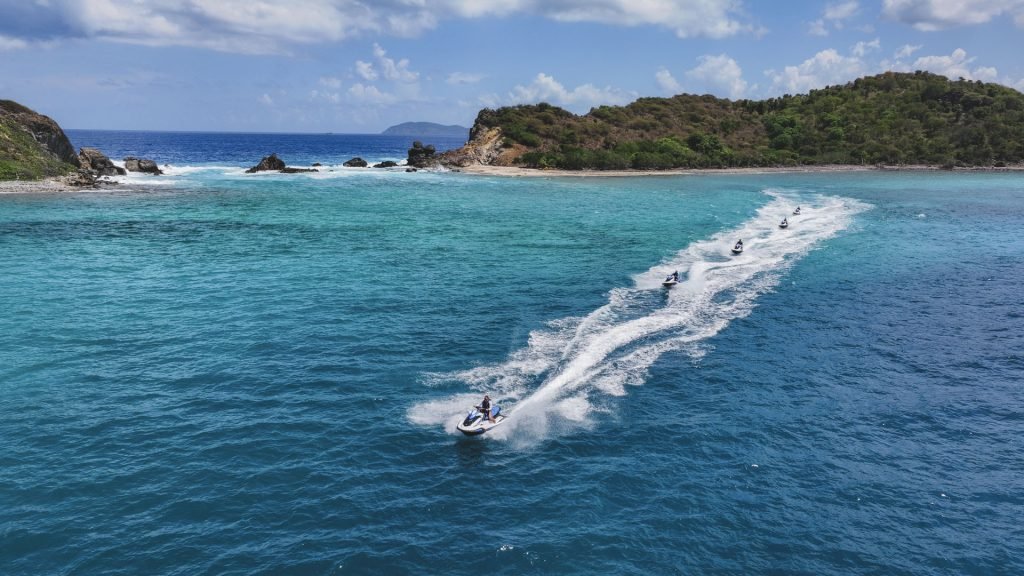 Jet skis speeding through turquoise waters near a tropical island with lush greenery.