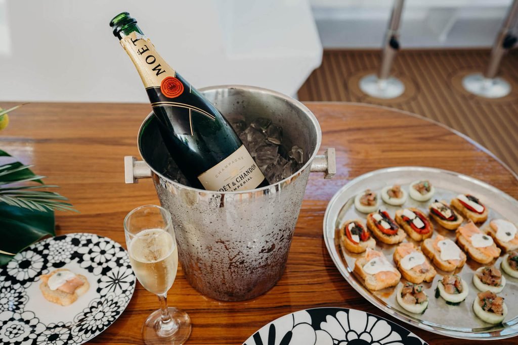 Bottle of Moët & Chandon champagne in ice bucket with glass and tray of appetizers.