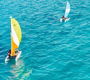 Two sailboats with colorful sails on a blue sea.