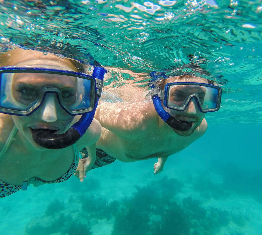 Two people snorkeling underwater in clear blue ocean.