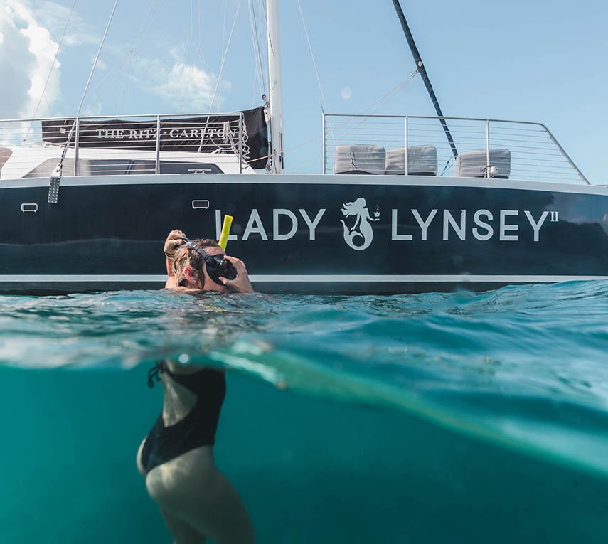 Person snorkeling near yacht 'LADY LYNSEY' in clear blue waters.