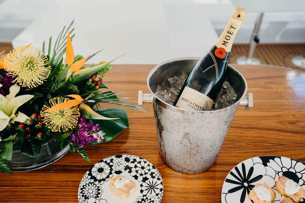 Bottle of Moët & Chandon champagne in ice bucket with glass and tray of appetizers.