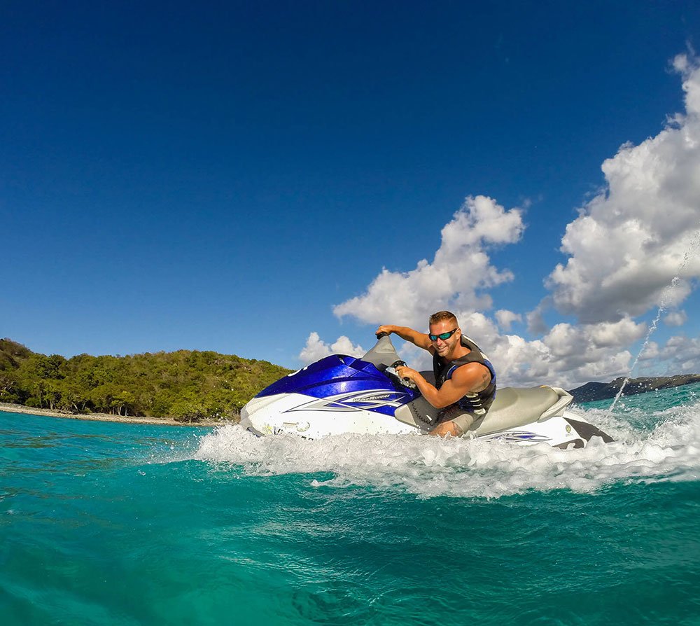 Jet ski rider on clear blue water with green island in the background