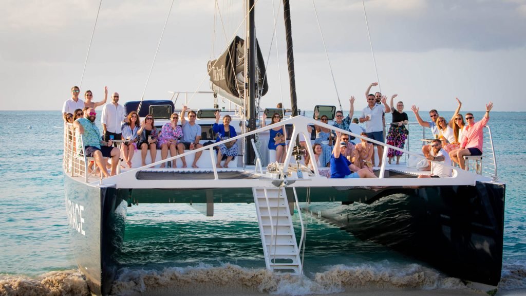 Group Of People Enjoying A Catamaran Trip On The Ocean With Clear Skies.