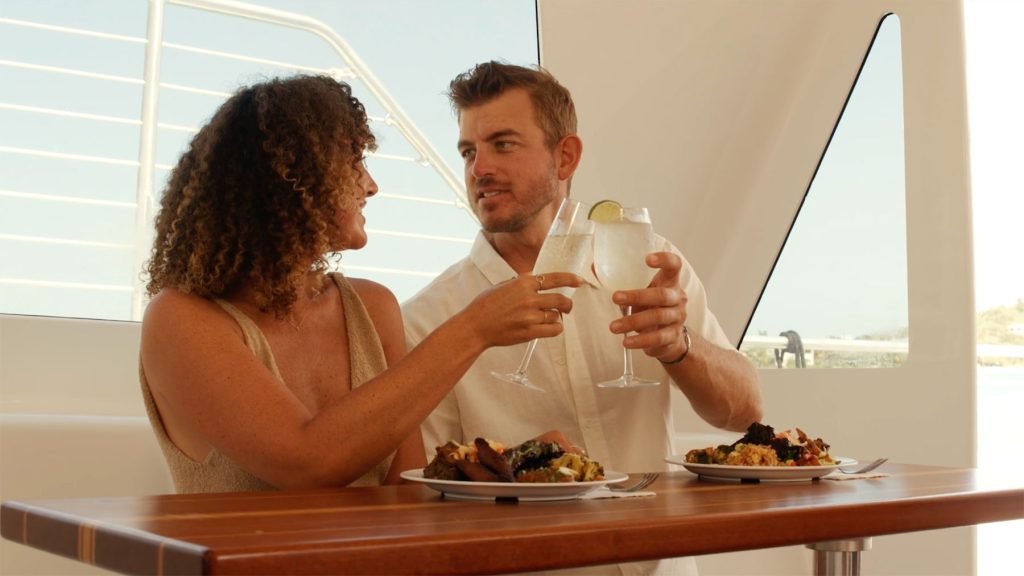Couple Enjoying A Meal And Drinks On A Yacht, Toasting With Glasses Of Lemon Water.