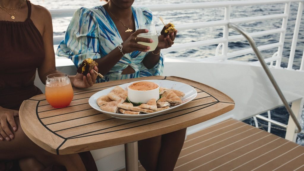 Group of friends enjoying a sailing trip with a picturesque view of the tropical coastline in the background