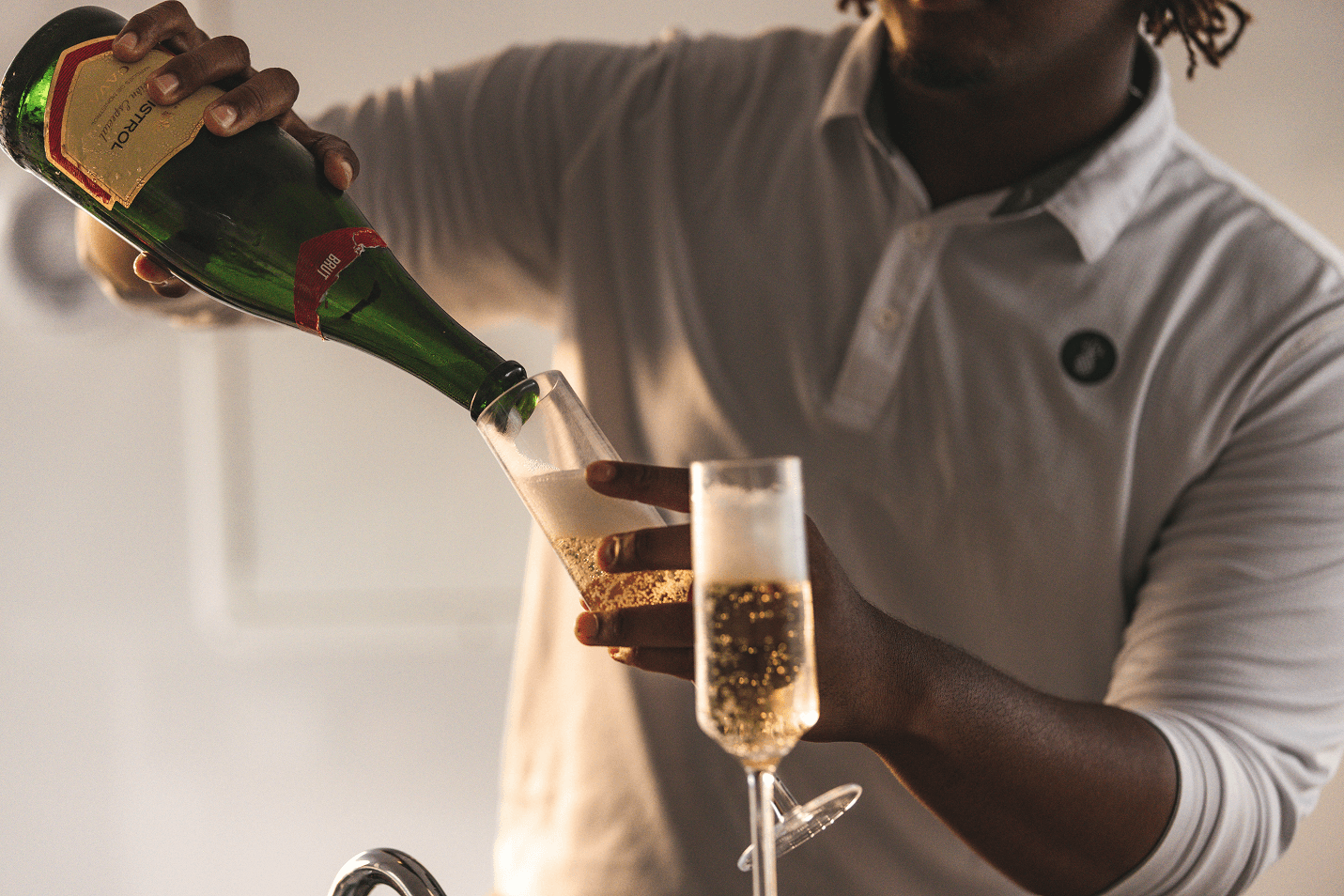 Sparkling beverage being poured into a flute glass, likely champagne or sparkling wine